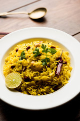 Lemon Rice is a South Indian turmeric rice or maharashtrian recipe called fodnicha bhat using leftover rice garnished with nuts curry leaves and lemon juice, selective focus