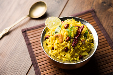 Lemon Rice is a South Indian turmeric rice or maharashtrian recipe called fodnicha bhat using leftover rice garnished with nuts curry leaves and lemon juice, selective focus