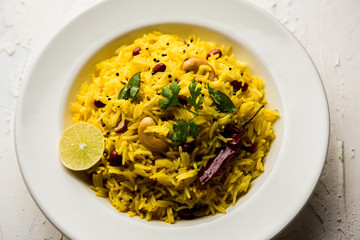 Lemon Rice is a South Indian turmeric rice or maharashtrian recipe called fodnicha bhat using leftover rice garnished with nuts curry leaves and lemon juice, selective focus