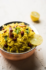 Lemon Rice is a South Indian turmeric rice or maharashtrian recipe called fodnicha bhat using leftover rice garnished with nuts curry leaves and lemon juice, selective focus