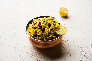 Lemon Rice is a South Indian turmeric rice or maharashtrian recipe called fodnicha bhat using leftover rice garnished with nuts curry leaves and lemon juice, selective focus