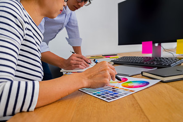 Graphic design with color swatches and tablet on a desk. Graphic designer drawing something on tablet at the office with work tools and accessories.