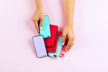 hands holding colorful smartphone cases. Pink Background