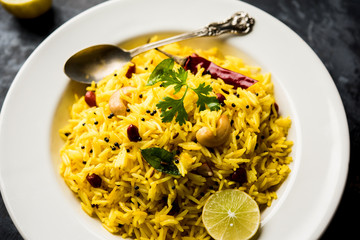 Lemon Rice is a South Indian turmeric rice or maharashtrian recipe called fodnicha bhat using leftover rice garnished with nuts curry leaves and lemon juice, selective focus