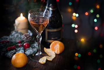 Rose wine and tangerines on the Christmas table with Christmas lights in the background