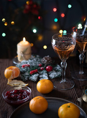Fototapeta na wymiar Rose wine and tangerines on the Christmas table with Christmas lights in the background