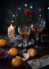 Rose wine and tangerines on the Christmas table with Christmas lights in the background