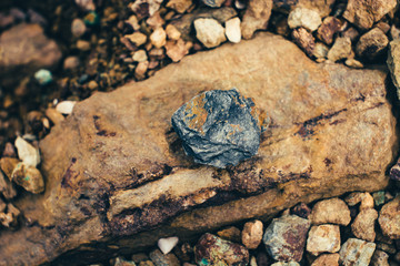 Raw ore on ground close-up. Multicolor rough stone in sunlight. Textured vivid geological...