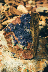 Raw ore on ground close-up. Multicolor rough stone in sunlight. Textured vivid geological background with pile of rude stones. Natural texture with copy space. Amazing mineral. Piece of rock.