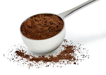 Grinded coffee powder in measuring scoop with beans isolated on white background