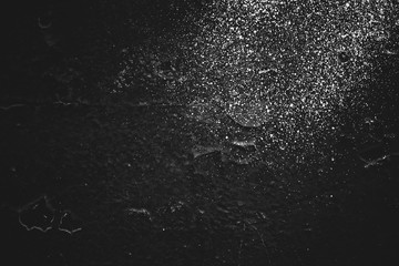 Dirty black wall close-up. Monochrome background with white sprays of dye. Black white texture of dark concrete wall with white spots. Painted backdrop in grayscale. Exfoliated paint. Flaking stucco.