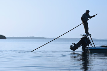 A fly fishing guide poling a flats skiff in search for tarpon and redfish along the coastline of south western Florida.