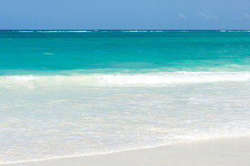 Tropical beach view with waves gently break on the shoreline on a sunny day, Diani, Kenya