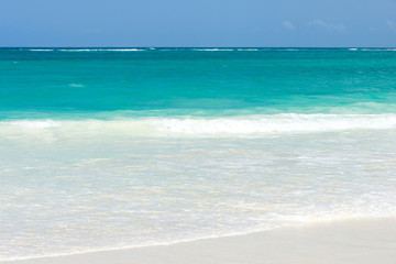 Fototapeta na wymiar Tropical beach view with waves gently break on the shoreline on a sunny day, Diani, Kenya