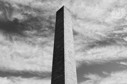 Detail of tall brick chimney extending towards cloudy sky 