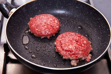 Two hamburgers frying in a pan