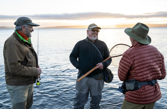Two fly fisherman talk wtih their guide about new tecnhiques while fly fishing for searun coastal cutthroat trout at a beach on the north west coastline of the USA. 