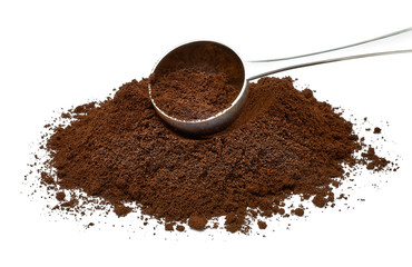 Grinded coffee powder in measuring scoop with beans isolated on white background