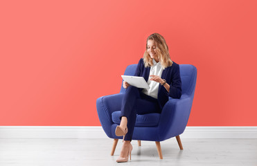 Young woman with tablet sitting in armchair indoors