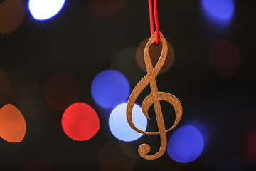 Wooden treble clef against blurred lights. Christmas music