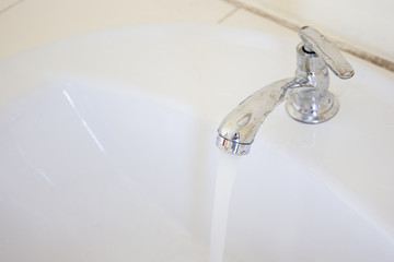 Water flowing from the stainless water tap close up.