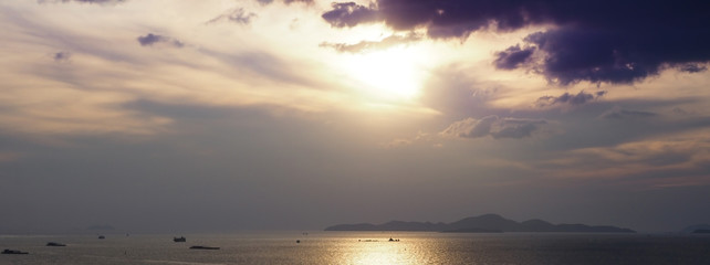 Beautiful seascape and a silhouette of mountain island in an evening sunset. Combination of clouds, sea and sunlight colors.