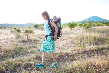 A woman is carrying a backpack with her baby.