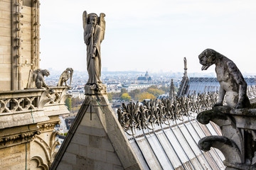 Stone statues of chimeras overlooking the rooftop of Notre-Dame de Paris cathedral from the towers...
