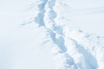 Fresh snow background texture. Winter background with snowflakes and snow mounds. Snow lumps. Footprints and traces.