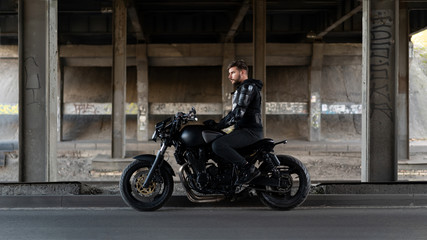 Guy on a black motorcycle motorcycle stay under the bridge
