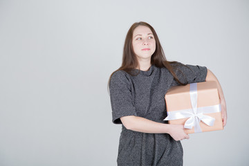 Portrait of a happy young woman in sunglasses isolated, holding present box