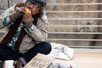 homeless man eating old bread on walkway street in the capital city..