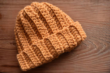 a tan crocheted hat isolated on wood