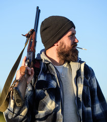 Hunting masculine hobby concept. Man brutal bearded guy gamekeeper blue sky background. Hunter with...