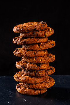 Chocolate chip cookies on rustic dark black background. Stacked chocolate chip cookies on brown napkin. Symbolic image with place for text. Freshly baked. Concept for a tasty snack. Sweet dessert. 