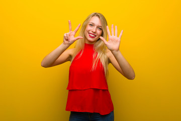 Young girl with red dress over yellow wall counting eight with fingers