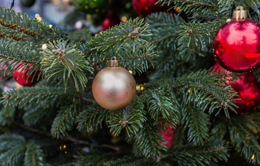 Christmas tree closeup. Red and golden balls and illuminated garland with flashlights.