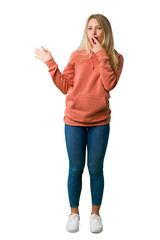 A full-length shot of a Young girl pointing finger to the side with a surprised face on isolated white background
