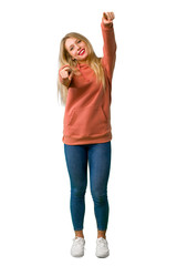 A full-length shot of a Young girl points finger at you while smiling on isolated white background