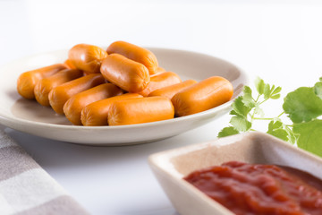 Sausage in a ceramic dish With ketchup Prepare to serve on a white table.