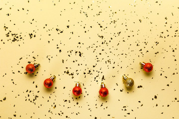 top view of red and golden christmas baubles and shiny confetti on beige background