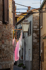 Fototapeta na wymiar Narrow small street of medieval town Castiglione d'Orcia where between houses linen dries, Italy
