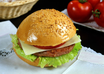 Pan de sésamo con una hamburguesa, lechuga, tomate y queso.
