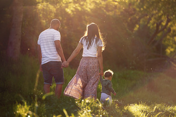 young family holding hands walking at sunset