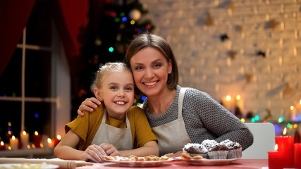 Cute mother and daughter looking into camera, Christmas preparations in family