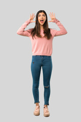 Full body of Teenager girl with pink shirt with surprise and shocked facial expression on isolated grey background