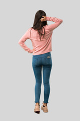Full body of Teenager girl with pink shirt on back position looking back while scratching head on...