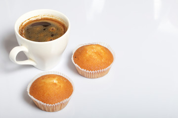 A cup of freshly brewed coffee and muffins. On a white background.