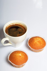 A cup of freshly brewed coffee and muffins. On a white background.