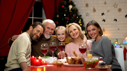 Big family hugging, smiling and looking to camera at Christmas dinner, portrait